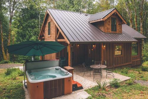a small cabin with a hot tub and an umbrella at Cedar Springs Cabin - Meredith Lodging in Welches