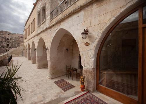 a building with arches and a courtyard with a table at Narcissos Cave Hotel in Urgup