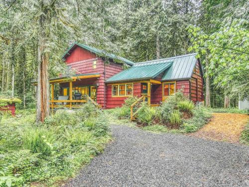 a red cabin with a green roof in the woods at Ripplewood - Meredith Lodging in Welches