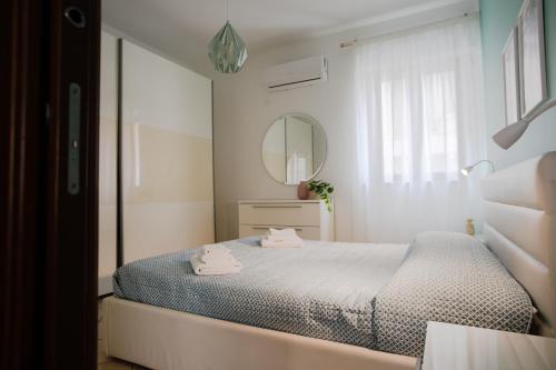 una camera bianca con letto e specchio di Cassaro Casa Vacanze a Castellammare del Golfo