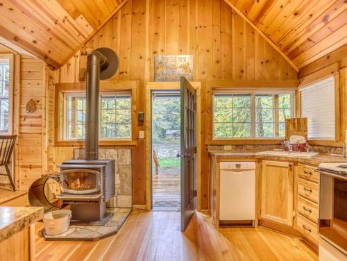 a log cabin kitchen with a wood stove at Thistle Dew - Meredith Lodging in Welches