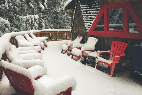 a row of chairs covered in snow next to a house at Cedar Creek Hideaway - Meredith Lodging in Welches