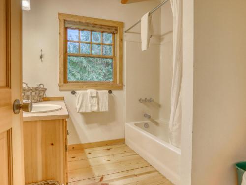 baño con lavabo, bañera y ventana en Marshall Cabin - Meredith Lodging, en Government Camp