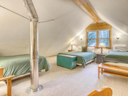 Un dormitorio abuhardillado con dos camas y una mesa. en Marshall Cabin - Meredith Lodging, en Government Camp