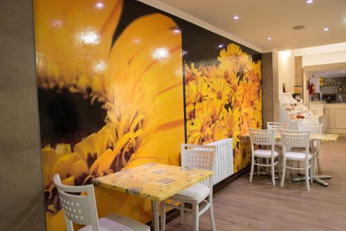 a restaurant with a table and chairs and a large painting at Hotel Paucam in Santa Teresita