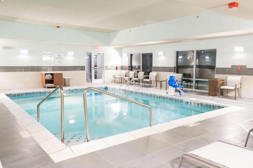 una piscina in una camera d'albergo con sedie e tavoli di Holiday Inn Express & Suites Dayton East - Beavercreek by IHG a Beavercreek