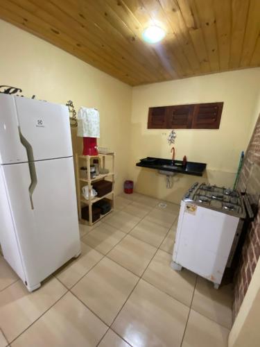a kitchen with a white refrigerator and a stove at Chalé Bela Vista - Chalés Belo Monte in Pacoti