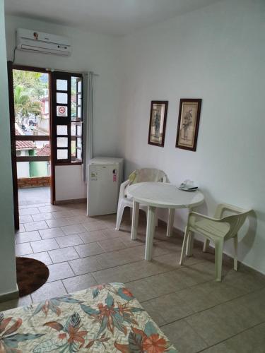Habitación con mesa, sillas y mesa blancas. en Pousada Recanto 3 Coqueiros, en Boicucanga