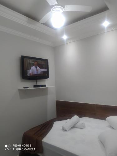 Habitación con 2 camas y TV en la pared. en Pousada Quarto Casal com ar,frigobar, garagem, en Aparecida