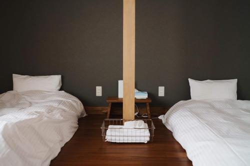 a room with two beds and a pole at RONENAI BASE in Biei