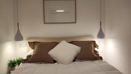 a bedroom with a bed with pillows and a picture at Apartamentos La Herradura Viñas in Haro