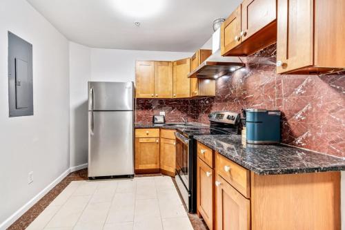 a kitchen with wooden cabinets and a stainless steel refrigerator at New and Cozy 1BD Apt in the heart of Philly! in Philadelphia