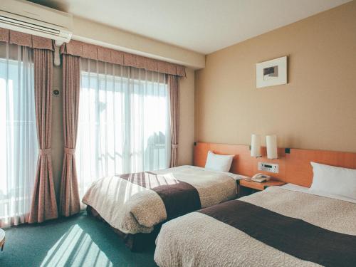 岡山市にあるくれたけイン岡山のベッド2台と窓が備わるホテルルームです。