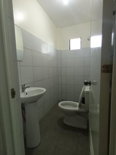 a white bathroom with a sink and a toilet at Grae’s Apartelle in Moalboal