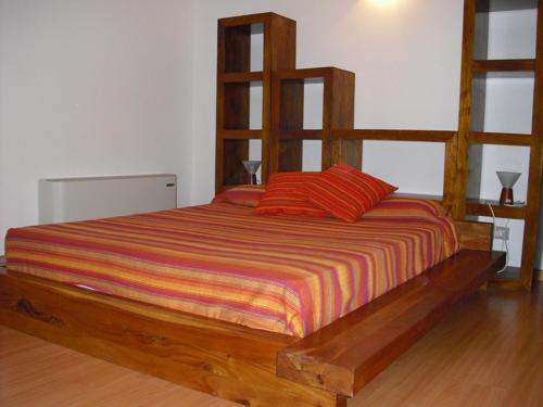 a wooden bed with two red pillows in a room at Villa Emiri in Cefalù
