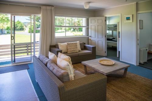 una sala de estar con un sofá y una mesa en Hahei Beach Resort, en Hahei