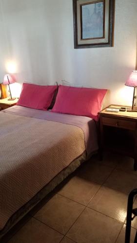 a bedroom with a bed with red pillows and a table at La Casa de Teresa in Colonia del Sacramento