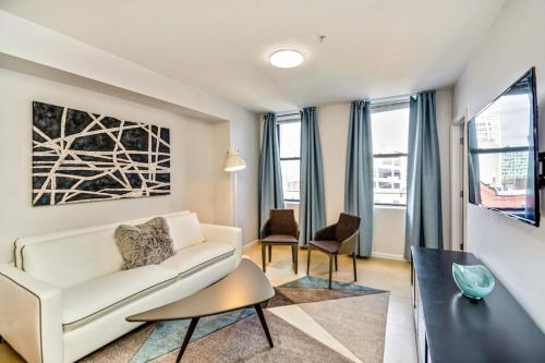 Forget the Hotel and stay in Style in a 2bd Apt في فيلادلفيا: غرفة معيشة مع أريكة بيضاء وطاولة