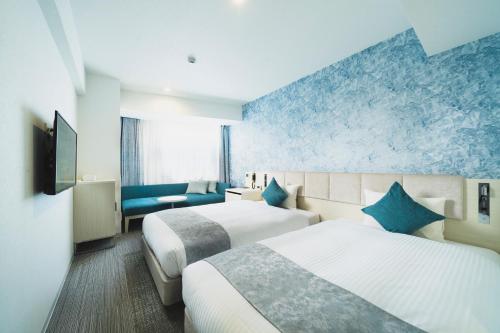 a hotel room with two beds and a blue wall at Rembrandt Style Naha in Naha