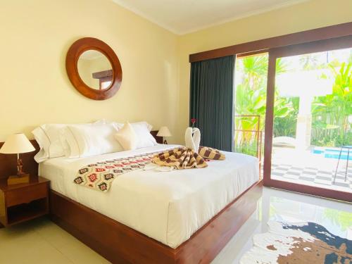 a bedroom with a bed with a mirror and a window at Villa Serenity in Lovina