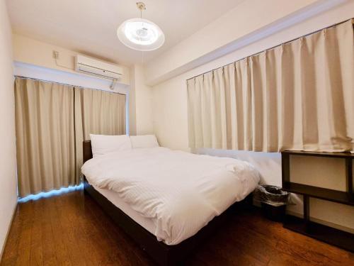 1 dormitorio con cama blanca y ventana en PRISM COURT 綾瀬 en Tokio