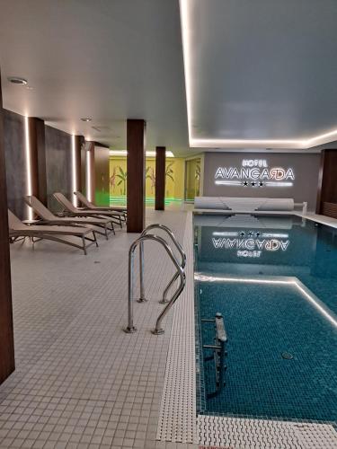 a swimming pool in a hotel room with a tub at Hotel Avangarda in Różan
