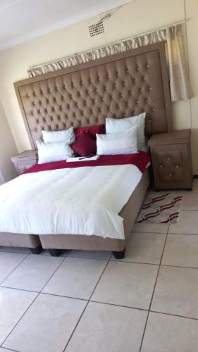 a bedroom with a large bed with a large headboard at 26 Zea avenue Arcon Park Guest House in Vereeniging