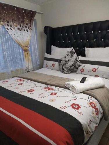 a bedroom with a bed with a bedspread with flowers on it at 26 Zea avenue Arcon Park Guest House in Vereeniging