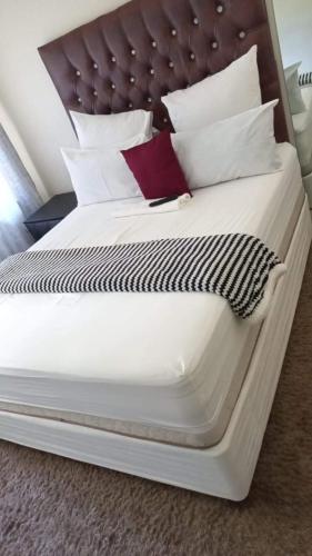 a large bed with white sheets and pillows at 26 Zea avenue Arcon Park Guest House in Vereeniging