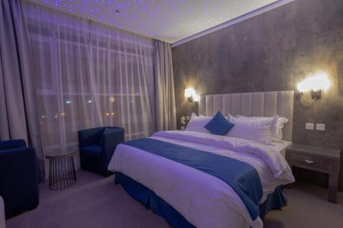 a bedroom with a large bed and a blue chair at Sweet Light Serviced Apartments in Tabuk