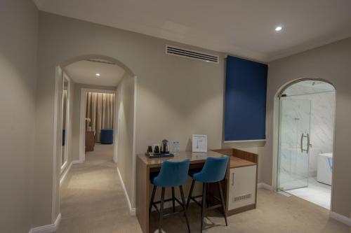 a bathroom with a counter and two blue bar stools at Sweet Light Serviced Apartments in Tabuk