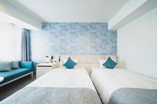 a bedroom with two beds and a blue couch at Rembrandt Style Naha in Naha