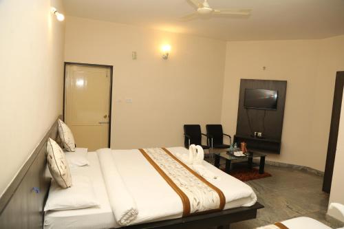 a hotel room with a bed and a tv at Soundarya Hotel in Bengaluru