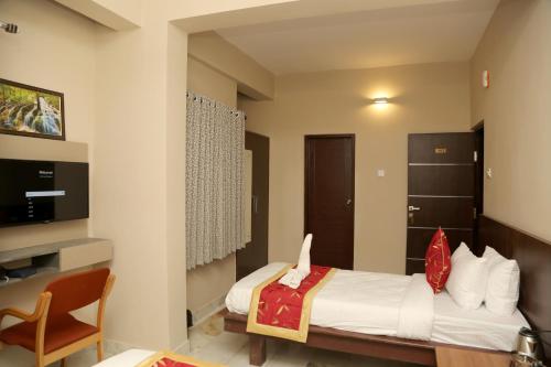 a hotel room with a bed and a chair at Soundarya Hotel in Bengaluru