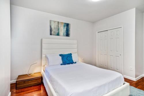 a white bedroom with a white bed with a blue pillow at Lovely 2bd Apt steps from the Convention Center in Philadelphia