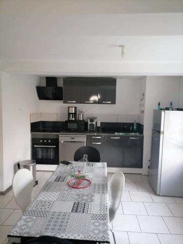 une cuisine avec une table avec des chaises et un réfrigérateur dans l'établissement Le pied à terre, à Feuquières-en-Vimeu