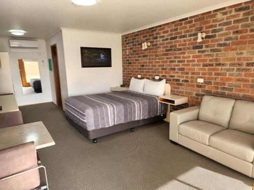 a bedroom with a bed and a brick wall at Country Roads Motor Inn Naracoorte in Naracoorte