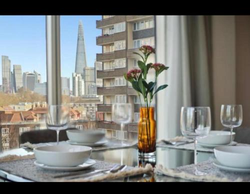 una mesa con platos y vasos y vistas a la ciudad en Prime Apartment en Londres