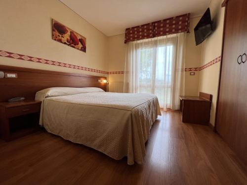 una camera d'albergo con letto e finestra di Viole Country Hotel ad Assisi