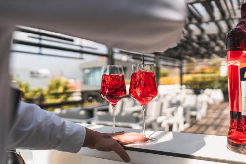 a person holding two wine glasses on a counter at Hotel Gartner in Tirolo