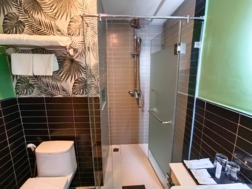 a bathroom with a toilet and a glass shower at VIVA LA VIDA HOTEL in Bangkok