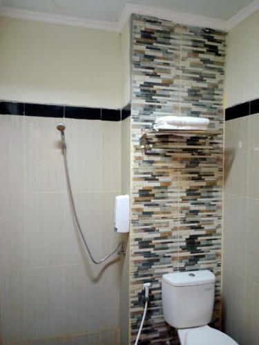a bathroom with a toilet and a stone wall at UNP Hotel & Convention in Padang