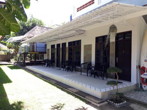 a patio of a house with chairs and tables at Manuh Guest House in Nusa Dua