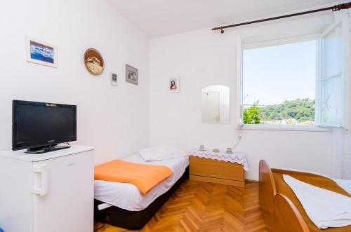 a room with two beds and a tv and a window at Guest House Mara in Dubrovnik