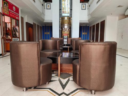 a restaurant with leather chairs and a table in a lobby at Zip By Spree Hotels Surabi International Vellore in Vellore