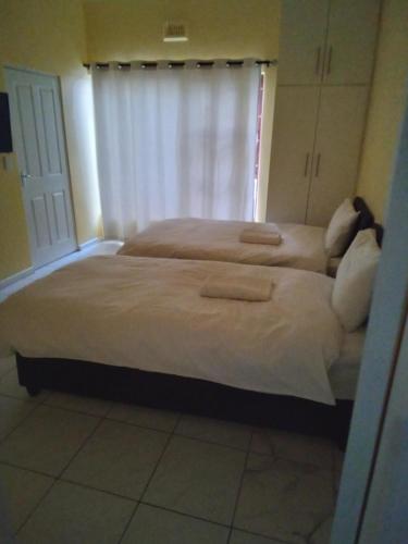 1 dormitorio con 2 camas con sábanas blancas y ventana en 24 on WRENCH, en Ciudad del Cabo
