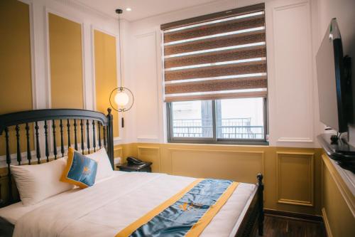 a bedroom with a bed and a window with a shutter at Alee Haiphong Hotel in Hai Phong