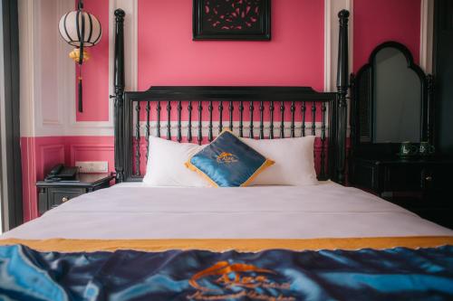 a bedroom with a large bed with pink walls at Alee Haiphong Hotel in Hai Phong