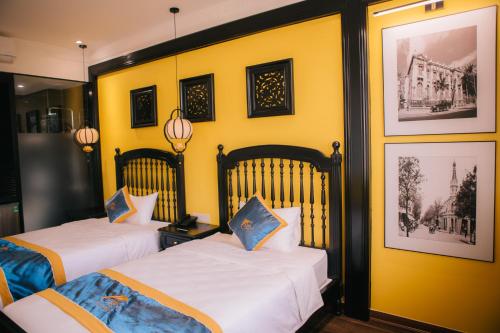 two beds in a room with yellow walls at Alee Haiphong Hotel in Hai Phong