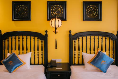 two beds in a room with yellow walls at Alee Haiphong Hotel in Hai Phong